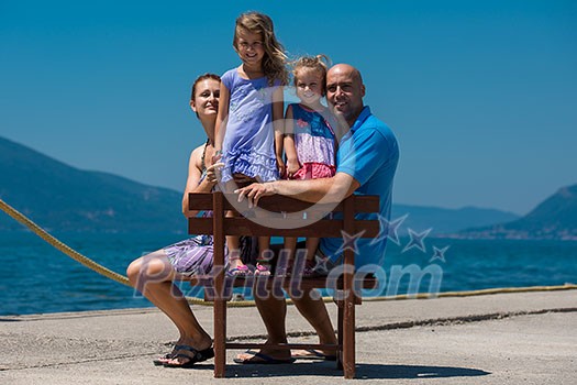 portrait of young happy family with cute little daughters having fun on a bench by the sea during Summer vacation Healthy family holiday concept portrait of young happy family with cute little daughters having fun on a bench by the sea during Summer vacation Healthy family holiday concept