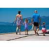 young happy family with cute little daughters holding their hands while walking by the sea during Summer vacation  Healthy family holiday concept