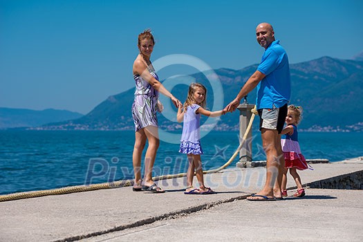 young happy family with cute little daughters holding their hands while walking by the sea during Summer vacation Healthy family holiday concept young happy family with cute little daughters holding their hands while walking by the sea during Summer vacation Healthy family holiday concept