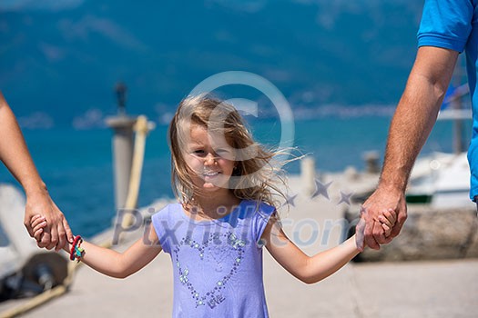 young happy family with cute little daughters holding their hands while walking by the sea during Summer vacation Healthy family holiday concept young happy family with cute little daughters holding their hands while walking by the sea during Summer vacation Healthy family holiday concept