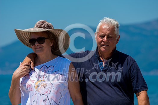 happy romantic senior couple hugging while walking  by the sea during Summer vacation