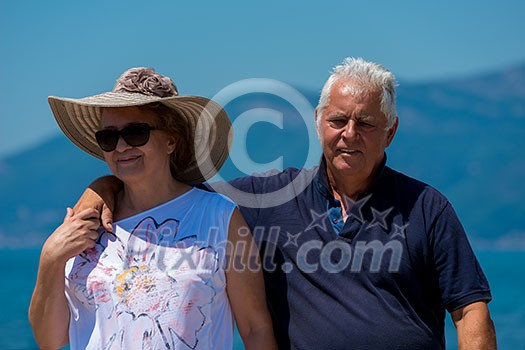 happy romantic senior couple hugging while walking by the sea during Summer vacation happy romantic senior couple hugging while walking by the sea during Summer vacation