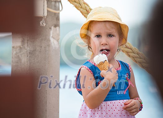 adorable little girl eating ice cream on beach by the sea during Summer vacation