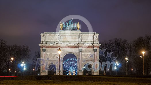 Paris, France - August 04, 2006: Night panorama of the Triumphal arch du Carrousel on the background of the Ferris wheel and luminous street lamps
