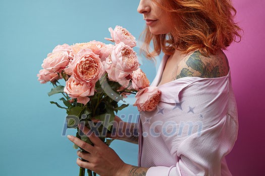 Pretty woman with tattoo holding bouquet of pink bouquet around a double blue pink background with copy space. St. Valentine's Day