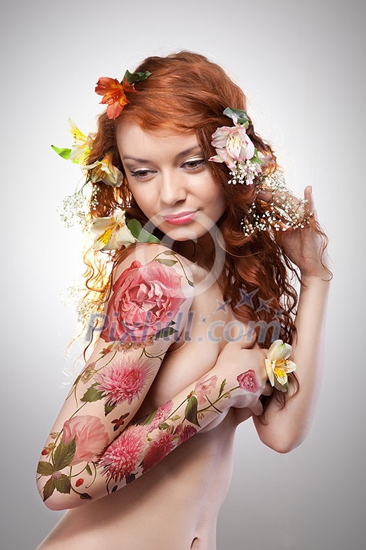 Red-haired girl with a floral tattoo and red hair decorated with flowers around a gray background with copy space. Spring layout