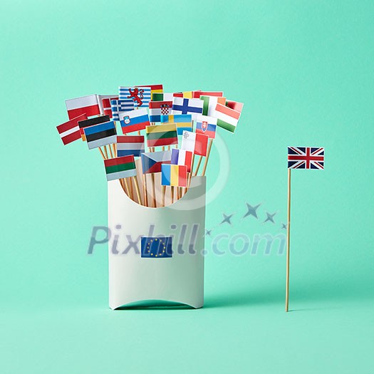 Paper flag of Britain and a cardboard box with a sign of the EU and a collection of different flags on a green background with copy space. The exit of Britain from the EU