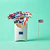 Paper flag of Britain and a cardboard box with a sign of the EU and a collection of different flags on a green background with copy space. The exit of Britain from the EU