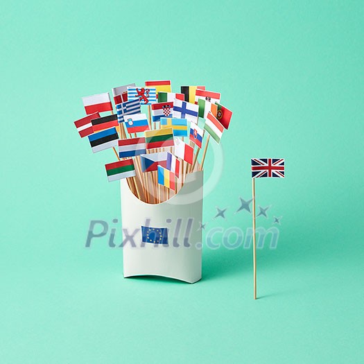 Different paper flags in a cardboard box with an EU sign and the flag of Britain aside on a green background . The exit of Britain from the EU