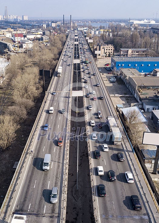 Aerial view from drone traffic overpass with moving cars and trucks on an asphalt road in a sunny spring day.