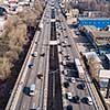 Aerial view from drone traffic overpass with moving cars and trucks on an asphalt road in a sunny spring day.