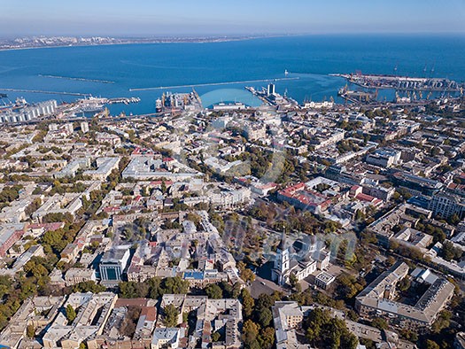 Panoramic view of the Black Sea with the port and the city from Spaso-Preobrazhensky Cathedral against the blue sky. Ukraine, Odessa. Aerial view from the drone