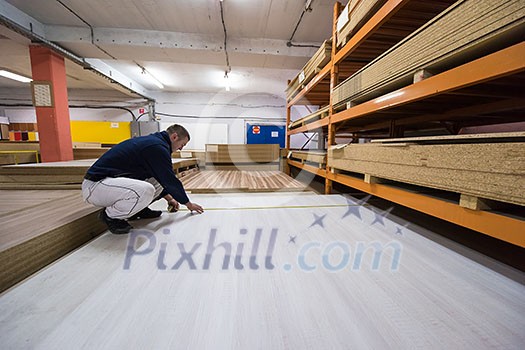 young man carpenter measuring wooden board for cutting while working in big modern carpentry High quality wood concept young man carpenter measuring wooden board for cutting while working in big modern carpentry High quality wood concept