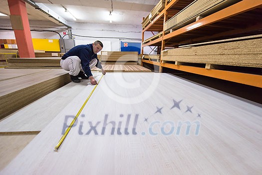 young man carpenter measuring wooden board for cutting while working in big modern carpentry High quality wood concept young man carpenter measuring wooden board for cutting while working in big modern carpentry High quality wood concept