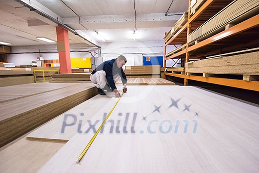 young man carpenter measuring wooden board for cutting while working in big modern carpentry High quality wood concept young man carpenter measuring wooden board for cutting while working in big modern carpentry High quality wood concept