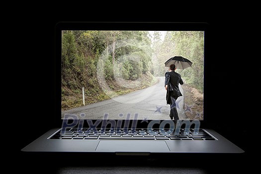 Small businessman with umbrella walking in to laptop screen. Mixed media