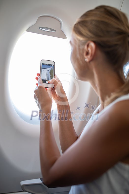 Young woman taking photos during flight in a modern airplane