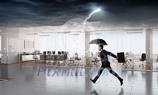 Businessman with umbrella facing storm in modern office. Mixed media Businessman with umbrella facing storm in modern office. Mixed media