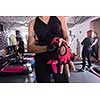 Young sporty woman putting on her sports gloves while preparing for training in the modern fitness studio