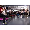 group of young healthy sporty women working out with instructor using barbells while exercises in a fitness studio  fitness, sport, training, gym and lifestyle concept