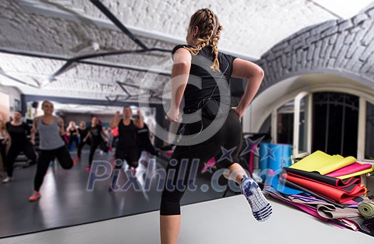 group of young healthy sporty women working out with instructor doing aerobics exercises in a fitness studio fitness, sport, training, gym and lifestyle concept