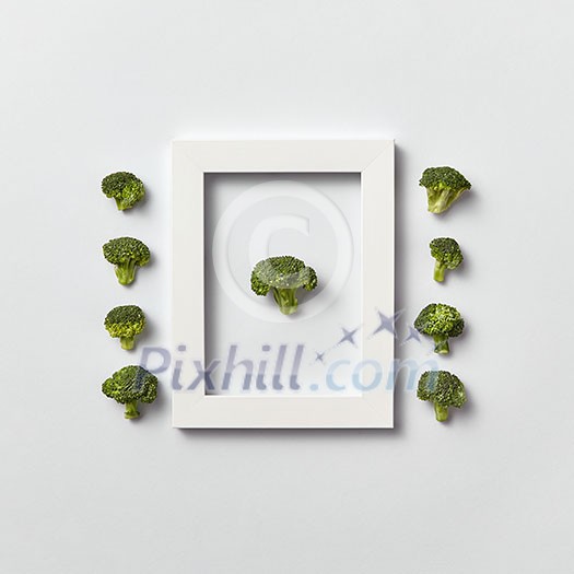 Creative organic composition with freshly picked green broccoli in a frame and out of it on a light gray background, place for text. Flat lay. Vegan concept. Creative organic composition with freshly picked green broccoli in a frame and out of it on a light gray background, place for text. Flat lay. Vegan concept.