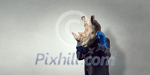 Businessman in boxing glove with rhino head. Mixed media Businessman in boxing glove with rhino head. Mixed media