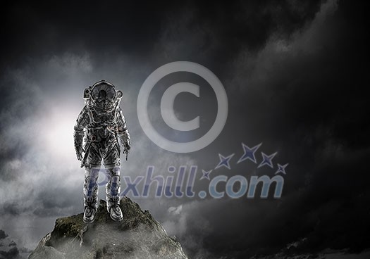Space explorer in astronaut suit at rock top. Mixed media