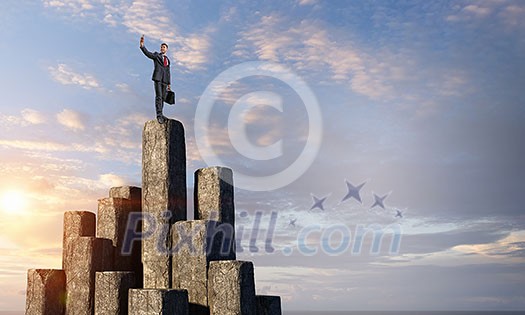 Businessman on top of stone column making selfie. Mixed media Businessman on top of stone column making selfie. Mixed media