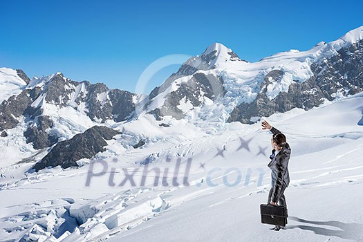 Businessman in suit among snowy mountains ready to overcome any challenge. Mixed media