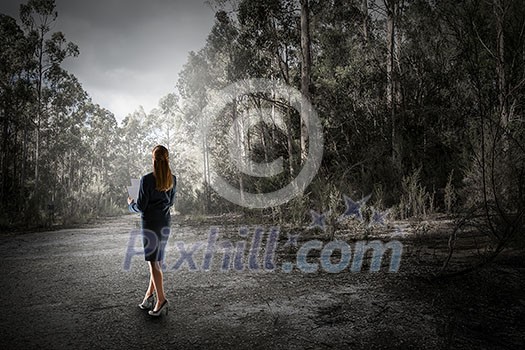 Young businesswoman with papers in hands in summer forest. Mixed media Young businesswoman with papers in hands in summer forest. Mixed media