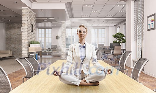 Attractive office woman sitting cross legged at workplace. Mixed media