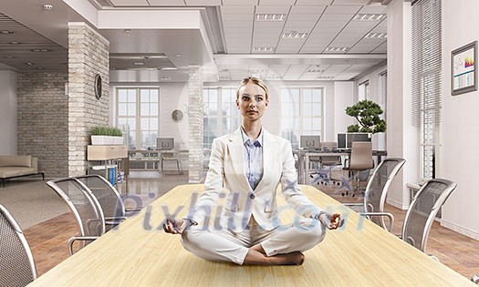 Attractive office woman sitting cross legged at workplace. Mixed media Attractive office woman sitting cross legged at workplace. Mixed media