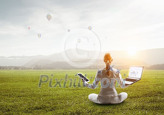 Elegant businesswoman sitting in lotus pose on green grass. Mixed media