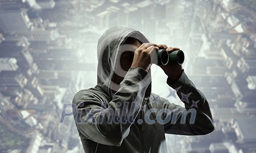 Unrecognizable man wearing hoody looking in to binoculars. Mixed media