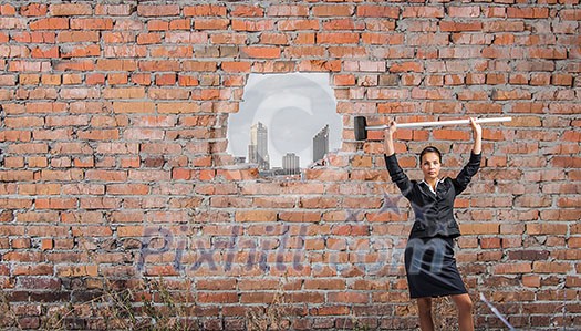 Businesswoman with hammer and hole in stone wall. Mixed media Businesswoman with hammer and hole in stone wall. Mixed media