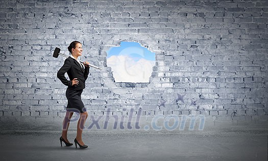 Businesswoman with hammer and hole in stone wall. Mixed media Businesswoman with hammer and hole in stone wall. Mixed media