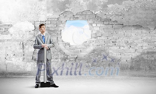 Businessman with hammer and hole in stone wall. Mixed media