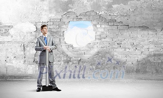 Businessman with hammer and hole in stone wall. Mixed media Businessman with hammer and hole in stone wall. Mixed media
