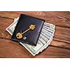 Dollar banknotes in leather purse and golden key on wooden table