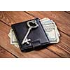 Dollar banknotes in leather purse and old vintage key on wooden table