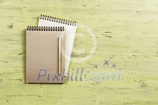Top view of two notepads with pencil on wooden background