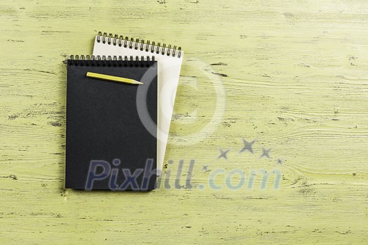 Top view of two notepads with pencil on wooden background Top view of two notepads with pencil on wooden background