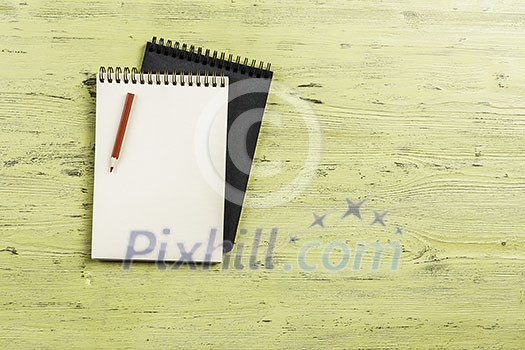 Top view of two notepads with pencil on wooden background Top view of two notepads with pencil on wooden background
