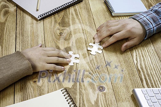 Woman and man sitting at table and assembling jigsaw puzzle Woman and man sitting at table and assembling jigsaw puzzle