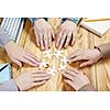 Group of people sitting at table and assembling jigsaw puzzle