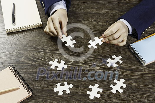 Hand of businesswoman completing puzzle with missing piece