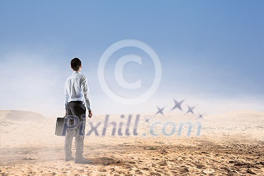 Businessman with suitcase standingn in sand desert Businessman with suitcase standingn in sand desert