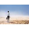 Businessman with suitcase standingn in sand desert