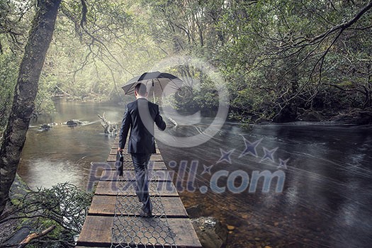 Businessman with umbrella walking alone in forest. Mixed media